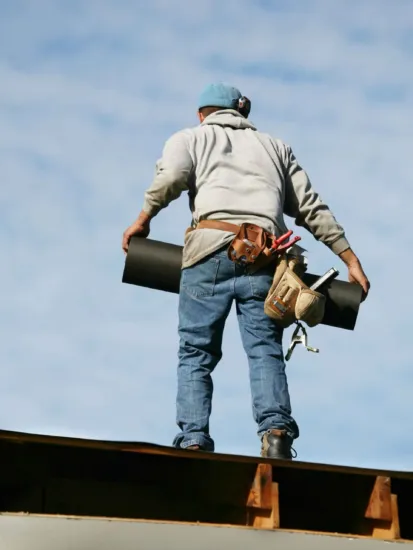 A roofer brings tiles to the work site on a new installation job.
